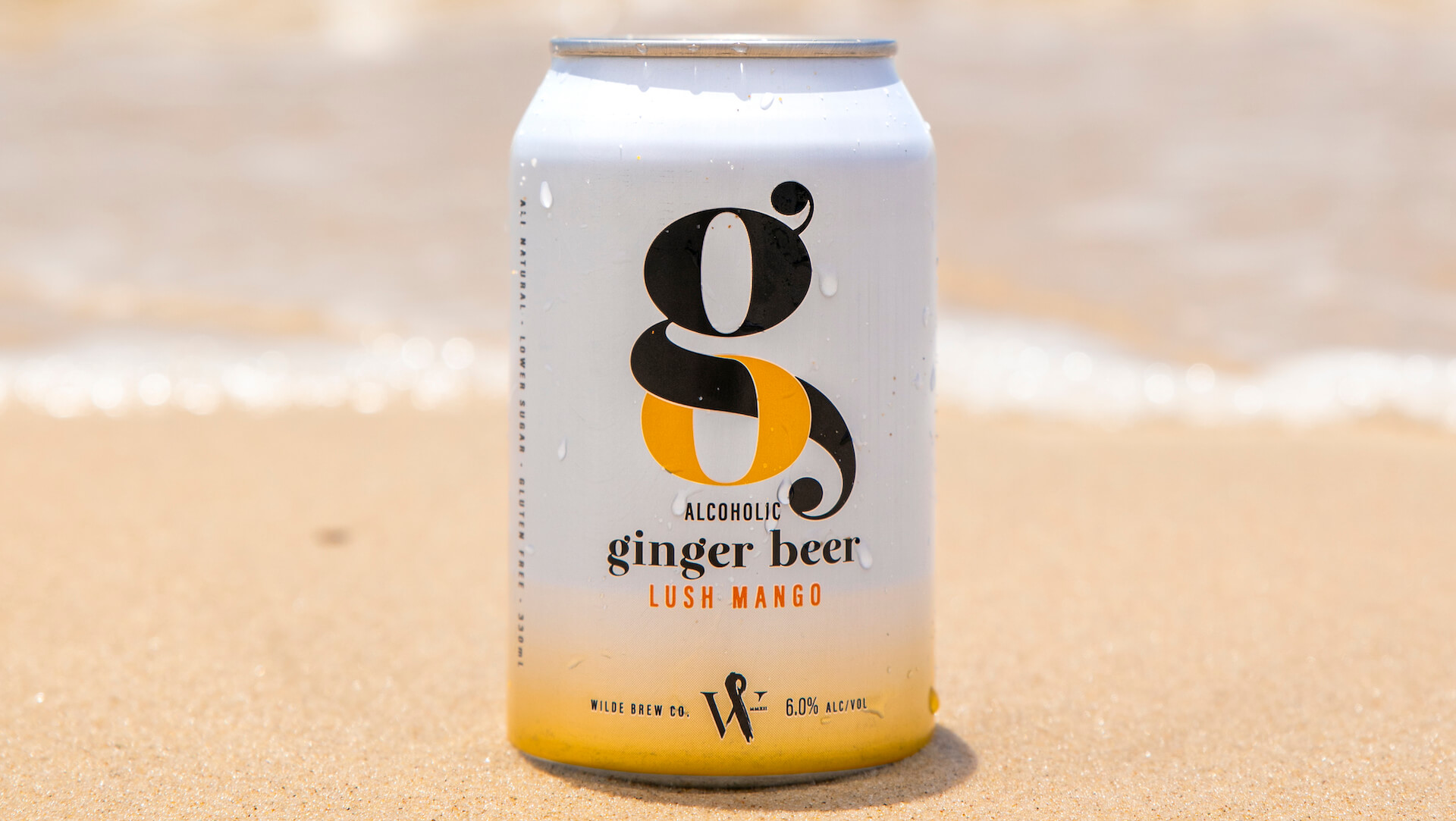 Can of Wilde Go Ginger Beer Lush Mango Flavour on the beach on a bright summer day