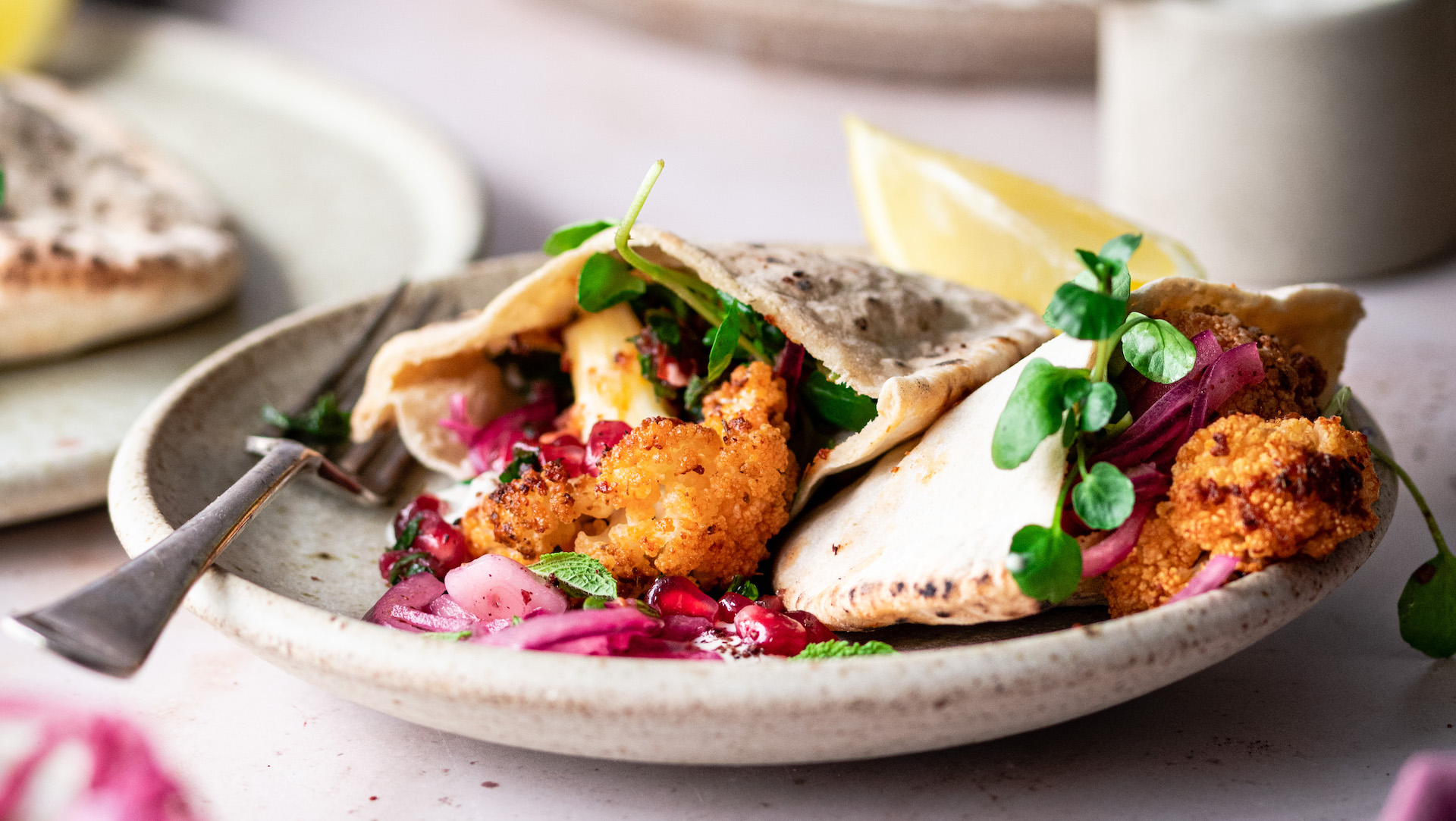 A pita bread stuffed with colourful spiced cauliflower, red onions and served with a lemon wedge